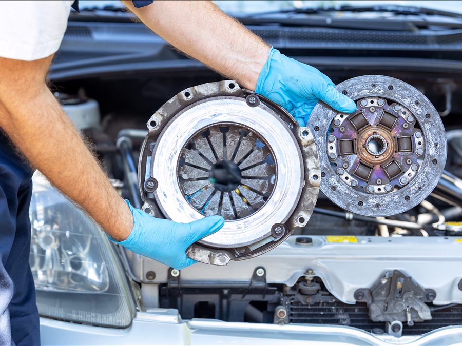A technician holding a clutch pressure plate and disc